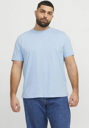 Helles blaues Baumwoll-T-Shirt mit kurzen Ärmeln, Rundhalsausschnitt und kleinem Logo auf der Brust, kombiniert mit mittelblauen Jeans.