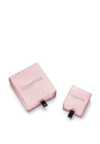 Dve ružové škatuľky so zlatými lístkovými vzormi. Väčšia škatuľka má pútko a obsahuje text "GLANZSTÜCKE MÜNCHEN." Menšia škatuľka je umiestnená vedľa nej.