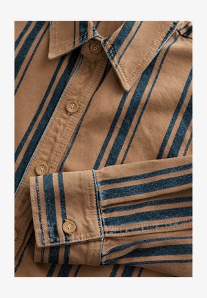 Hnedá pruhovaná košeľa s modrými vertikálnymi líniami, s golierom na gombiky a dvoma gombíkmi na légovej časti. Hladká tkanina s jemným detalom šitia.