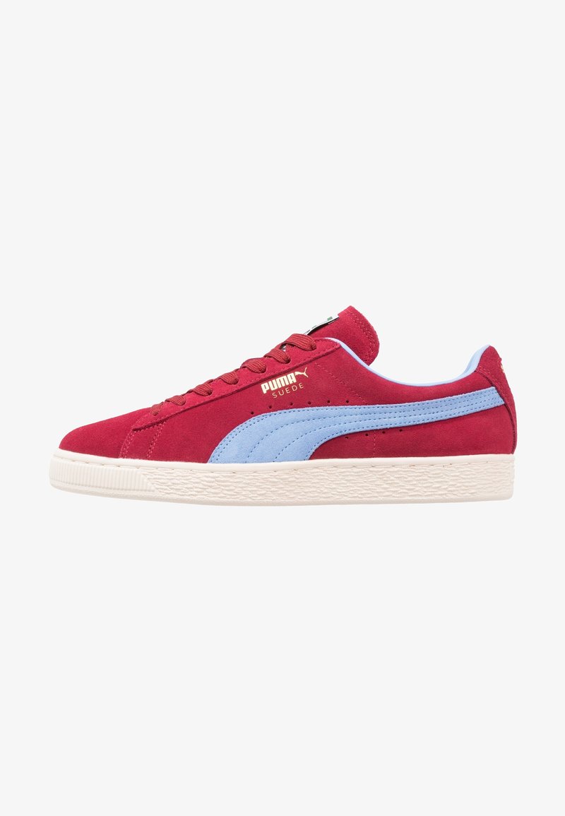 Červené semišové tenisky s světle modrým pruhem, s texturovanou gumovou podrážkou. Zlaté logo "PUMA SUEDE" na boku. Klasický design na šněrování.