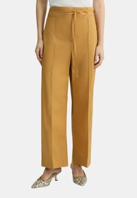 Pantaloni a vita alta di colore senape chiaro con un design affusolato e cintura coordinata. Tessuto liscio con dettagli della cucitura laterale e tasche.