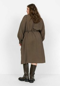Vestido a rayas marrón y beige con mangas globo y cintura fruncida; combinado con botas marrones hasta la rodilla con hebillas.