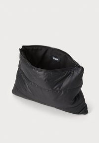 Bolso de mano acolchado negro con cierre de cremallera, que presenta una textura suave y brillante y una etiqueta de logo en el interior. Forma triangular con detalle de acolchado.