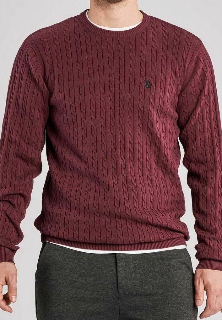 Pull bordeaux en maille torsadée avec col rond, présentant des motifs texturés et un petit emblème sur la poitrine, assorti à un pantalon gris.
