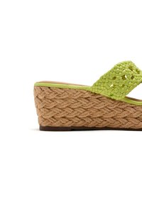 Sandalia de cuña con base de yute trenzado. Tira tejida verde. Suela texturizada. Forma redondeada con acentos marrones en contraste en la parte inferior.