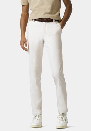 Weiße Baumwollhose mit schlanker Passform und glatter Textur, kombiniert mit einem braunen geflochtenen Gürtel und weißen High-Top-Sneakern.