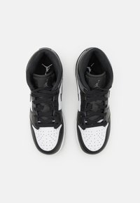 Des baskets montantes noir et blanc avec un dessus en cuir lisse, une pointe perforée, des lacets noirs et un petit logo sur la languette et sur le côté.