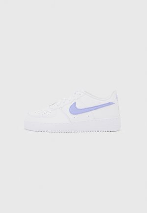 Baskets blanches basses Nike avec logo swoosh violet et perforations sur l'avant, présentées sur un fond gris clair uni.