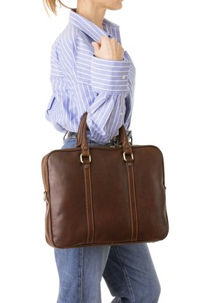 Borsa per laptop in pelle marrone con due manici superiori, dotata di hardware dorato e dettagli cuciti, tenuta da una persona con una camicia a righe.