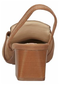 Brązowy koturn zamszowy z gładkim, jasnobrązowym wnętrzem, wyposażony w zakrzywiony pasek i przeszycia z tyłu obcasa.