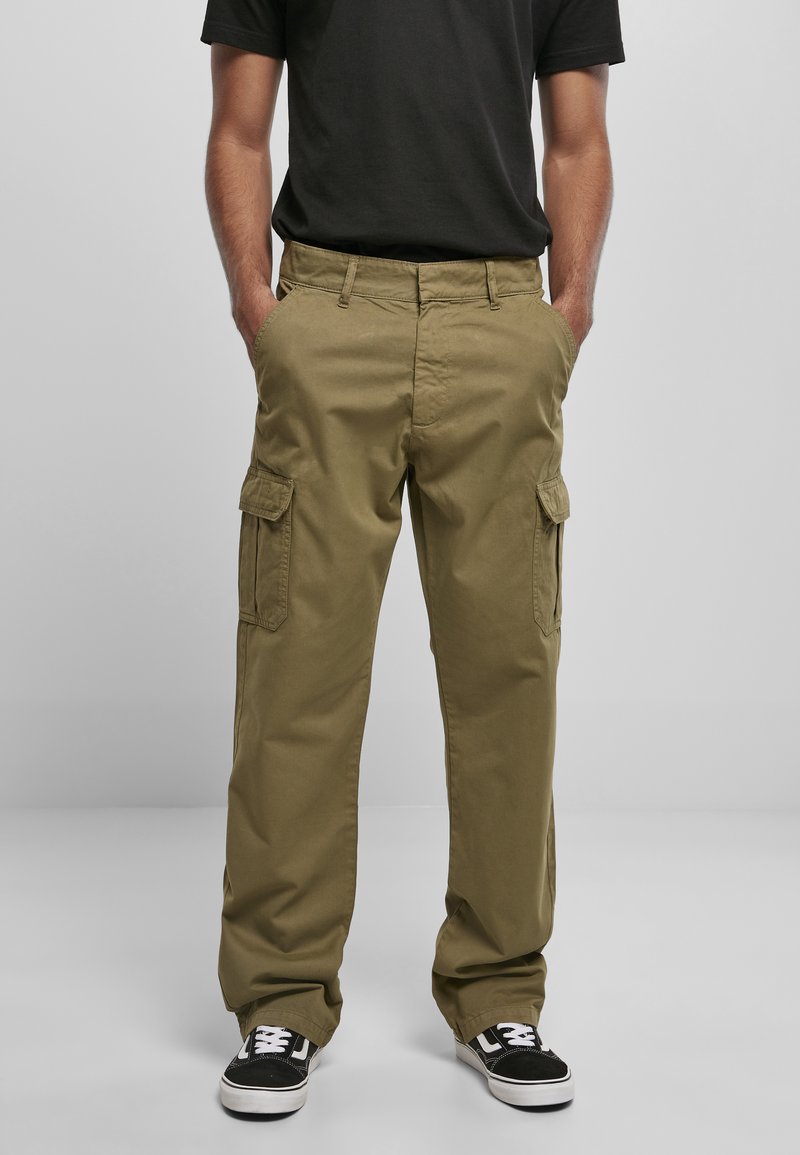 Pantalons cargo en vert olive, fabriqués en tissu durable, avec des poches latérales, une coupe décontractée et des baskets noires avec des accents blancs.