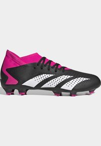 Mustat ja vaaleanpunaiset jalkapallokengät, joissa on synteettinen päällinen, verkkomaiset yksityiskohdat, kuusi nappulaa ja matala leikkaus. Korostetut valkoiset raidat ja rei'itykset.