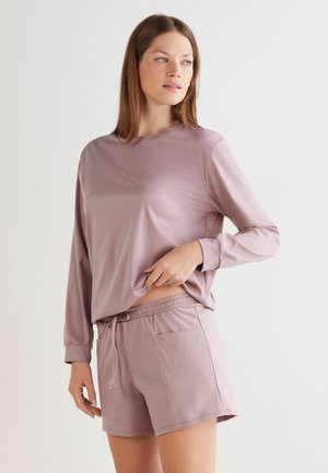 Ljuslila långärmad topp i kombination med matchande shorts. Toppens design har en rund halsringning, och shortsen har resår i midjan och fickor.