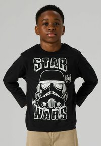 Black long-sleeve shirt featuring a white Stormtrooper graphic and "STAR WARS" text, made of cotton with a smooth texture.