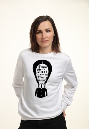White sweatshirt featuring a black graphic design with text and a figure, highlighting a balloon shape and stylized lettering.