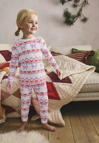 White cotton pajamas featuring pink bows and red hearts in a geometric pattern. Fitted design with long sleeves and leggings.