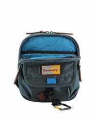 Zaino in tessuto blu e grigio con chiusura a zip superiore, etichetta patch esterna e due scomparti interni. Presenta un clip per il fissaggio.