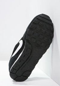 Czarne tenisówki z teksturowaną cholewką, białym logotypem oraz wzorzystą gumową podeszwą z głębokim bieżnikiem zapewniającym przyczepność.