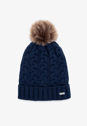 Navy knitted beanie with cable pattern, featuring a fluffy brown faux fur pom-pom on top and a ribbed cuff with a small logo patch.