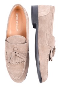 Mocassini in suede beige con design a moccasino, caratterizzati da un dettaglio a frange e una suola in gomma nera. Finiture cucite lungo i bordi.