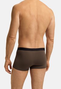 Pantaloni boxer in cotone marrone con cintura blu navy, caratterizzati da una consistenza liscia e un design adatto al corpo, mostrati di schiena senza camicia.
