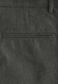 Tissu gris foncé avec un tissage texturé, comportant une poche passepoilée horizontale et une ceinture lisse. Design minimaliste, sans matériel visible.
