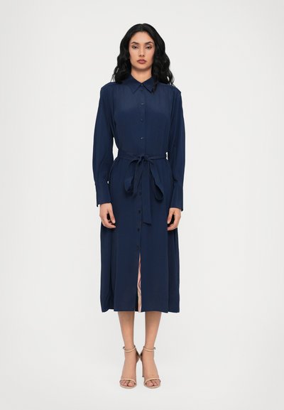 Vestido azul marino de manga larga, hecho de una tela suave, con cuello, botones en la parte delantera y un cinturón atado en la cintura. Falda ligeramente acampanada.