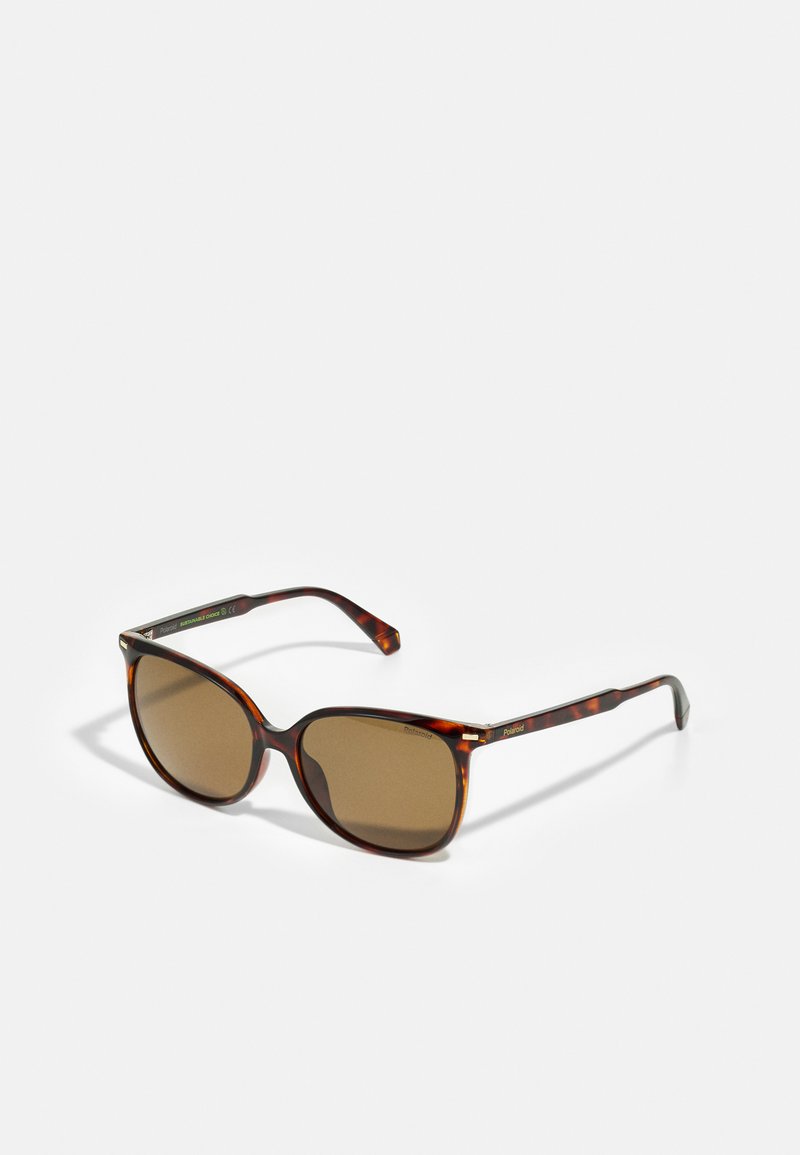 Occhiali da sole tartarugati con lenti marroni, forma ovale oversize e stanghette sottili con un logo discreto sulle cerniere.