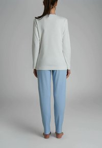 Maglia a maniche lunghe grigia chiara abbinata a pantaloni da pigiama a righe blu chiaro, caratterizzati da una vestibilità rilassata, una texture morbida e un design alla caviglia.