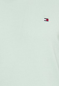 Helles mintgrünes Strickpullover mit geripptem Muster. Verfügt über ein kleines gesticktes Logo in Rot, Weiß und Blau auf der Brust.