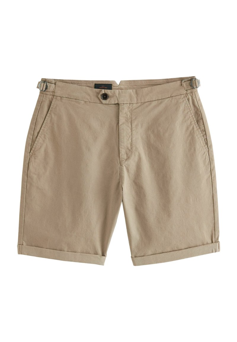 Shorts en coton beige au toucher lisse, dotés de deux poches avant, d'une fermeture à bouton et de bretelles ajustables sur les côtés.