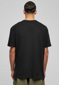 T-shirt en coton noir avec une coupe décontractée, des manches courtes et un col rond, présentant une texture lisse et un ourlet droit.