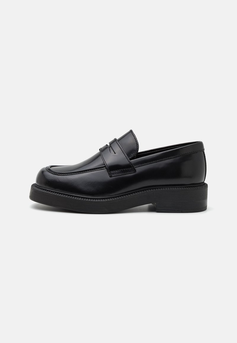 Mocassin en cuir noir avec un bout arrondi, des coutures décoratives à l'avant et une semelle en caoutchouc épaisse. Texture lisse avec une finition brillante.