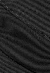 Black ribbed textile with horizontal and vertical lines, featuring a smooth texture and contrasting stitching. Suitable for activewear applications.
