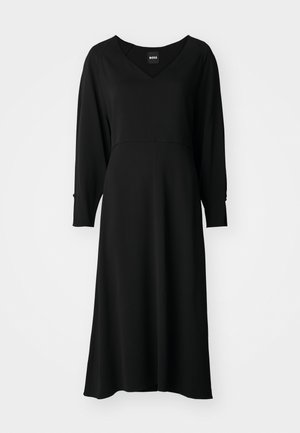 Fekete ruha hosszú ujjakkal, V-nyakkal, lezser fazonnal, térdhez érő hosszúságban, és ívelt mellrésszel. Puha anyag, amelynek enyhe fényessége van, és strukturált varrásokkal rendelkezik.