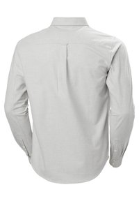 Camisa de manga larga gris claro con pliegue en la espalda, cuello tipo punta y puños con botones; textura de tela suave, diseño ajustado.