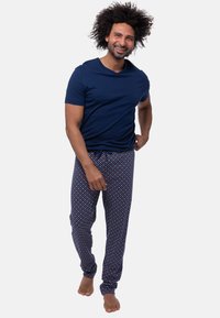 Navyblauwe T-shirt met korte mouwen in combinatie met gestreepte pyjamabroek met een navy achtergrond en kleurrijke stippen. Casual pasvorm, zachte textuur.