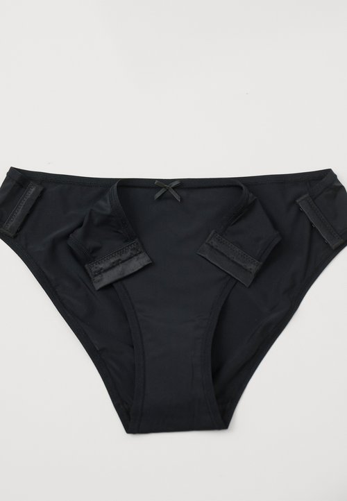 Bikini noir avec une texture lisse, doté de bretelles latérales réglables et d'un nœud décoratif central au niveau de la taille.