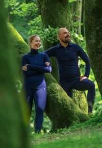 Marinblå utomhus träningsset i mjukt, elastiskt material. Innehåller en tröja med dragkedja vid halsen och tajta leggings, designade för komfort och rörelsefrihet.