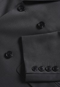 Tumehall täpselt sobiv ülikonnajakk, millel on tekstuuriga kangas, ees kuus musta nuppu ja tasku nelja sama nuppuga.