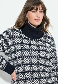 Granatowy sweter dziany z białym geometrycznym wzorem, z dodatkowym prążkowanym golfem i mankietami. Miękka tekstura i luźny krój.