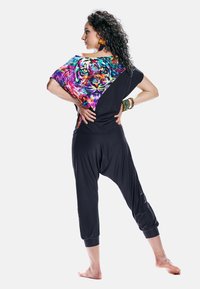 Tenue noire mettant en avant un graphique coloré de tigre sur l'épaule, coupe loose avec des poignets élastiques, et texture légère et douce.