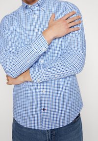 Blaue und weiße kariierte Hemdbluse mit langen Ärmeln, aus Baumwolle, mit abgerundetem Saum und klassischem Kragen.