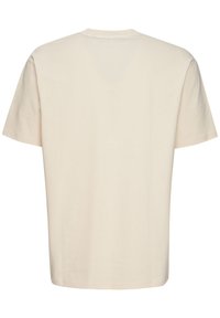 Lys beige t-shirt med rund hals og korte ærmer. Stoffet ser blødt ud med en glat tekstur. Ingen synlige mønstre eller grafik.