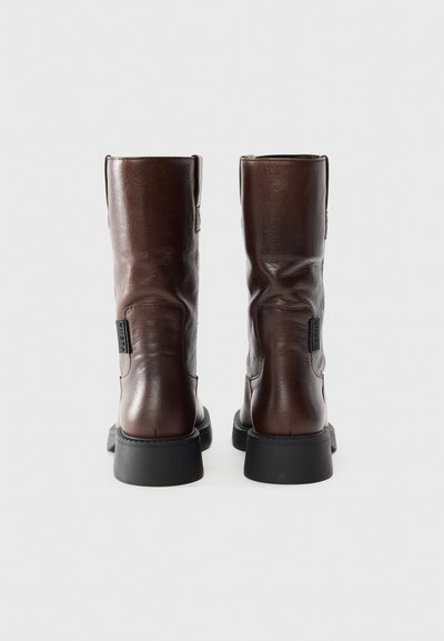 Brown leather ankle boots with a smooth texture, rounded toes, and a black rubber sole. Includes a side tag detail for branding.