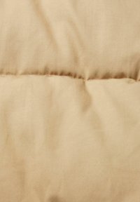 Tela acolchada beige con textura suave y un brillo sutil, con costuras horizontales espaciadas uniformemente que crean secciones acolchadas.