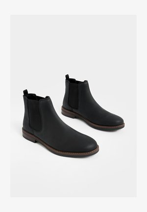 Schwarze Leder-Stiefel mit elastischen Seitenteilen, runden Spitzen und niedrigem, gestapeltem Absatz. Verfügt über Steppnähte und Schlaufen zum leichteren Anziehen.