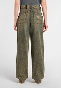 Högmidjade, vida jeans i texturerad, urtvättad grön denim. Har två bakfickor och kontrasterande sömmar. Knappar och dragkedja.
