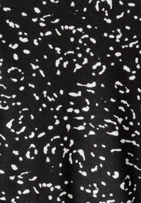 Tissu noir avec de petites formes blanches irrégulières et dispersées ressemblant à un motif ponctué aléatoire.