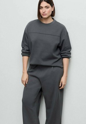 Sweat-shirt gris avec un col rond et des épaules tombantes, associé à un pantalon large assorti. Tissu doux avec une texture lisse.